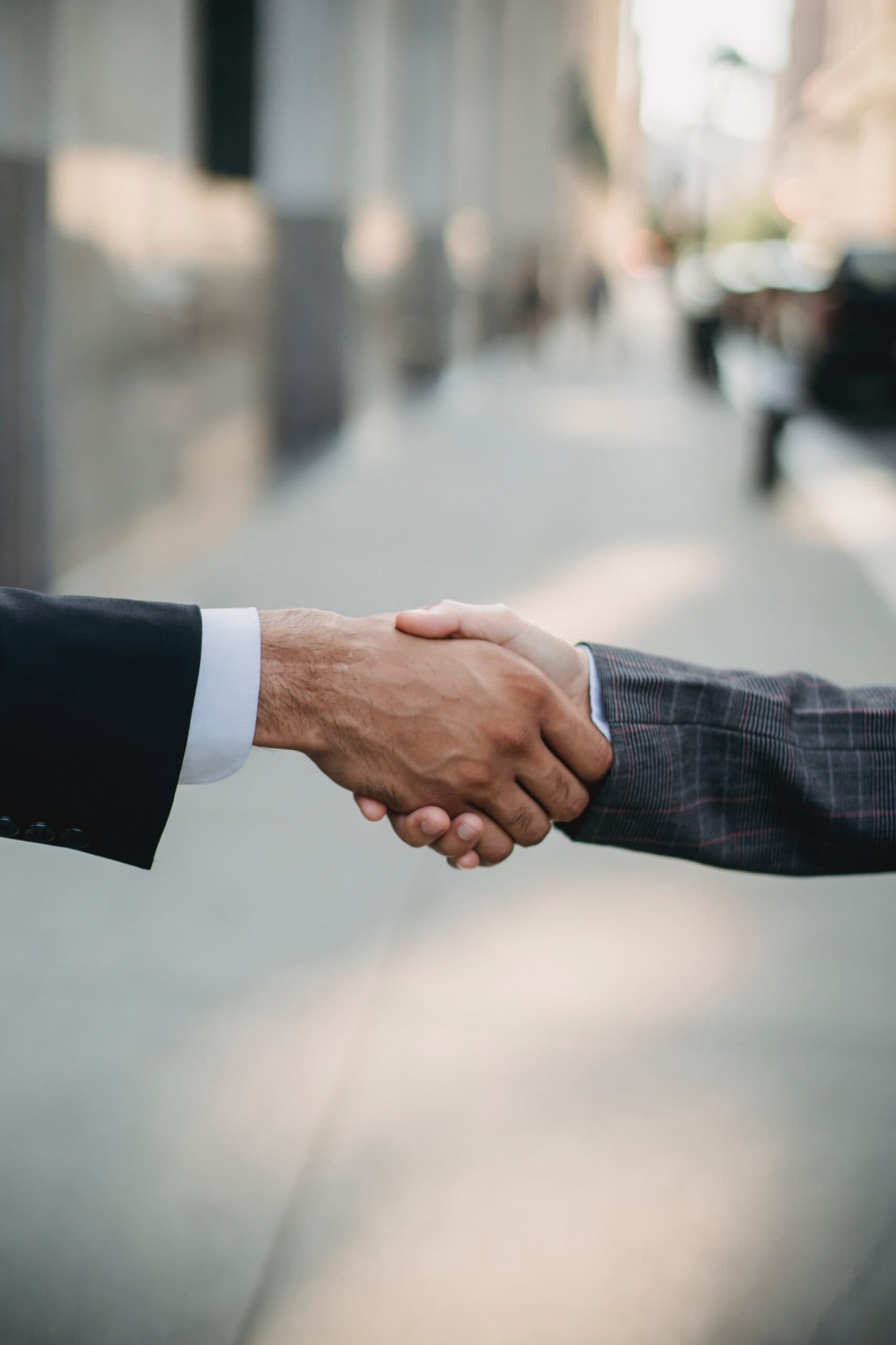 Two business people shaking hands, representing a small business owner partnering with outsourcing experts.