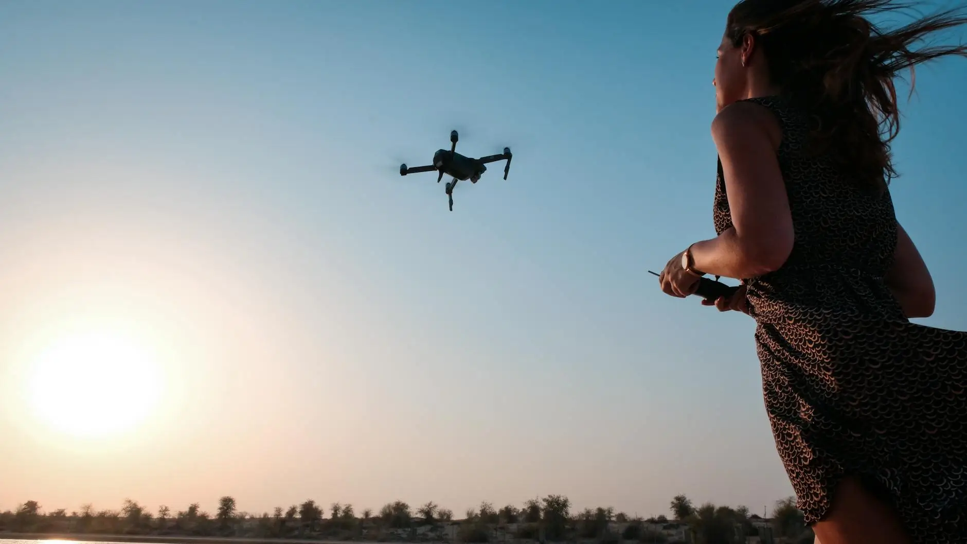 Woman controlling a drone at sunset in Dubai desert, illustrating UAE flying taxi innovation and urban air mobility