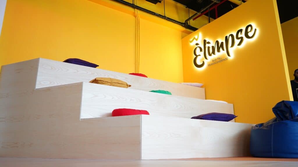 Glimpse Digital Agency office interior featuring a vibrant yellow backdrop and modern seating steps